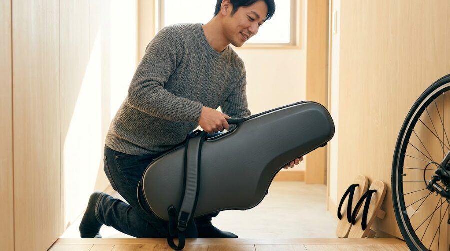 自宅の玄関で、超軽量なテナーサックスケースを片手で軽々と持ち上げる日本人男性